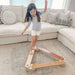 Child playing with a wooden balance beam in a living room.