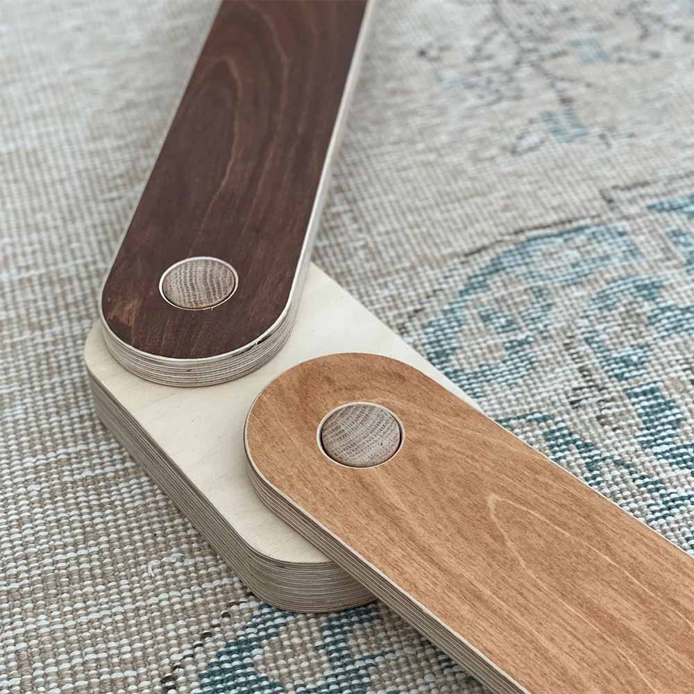 Close-up of a wooden balance beam with a dark wood stain color on a textured fabric background