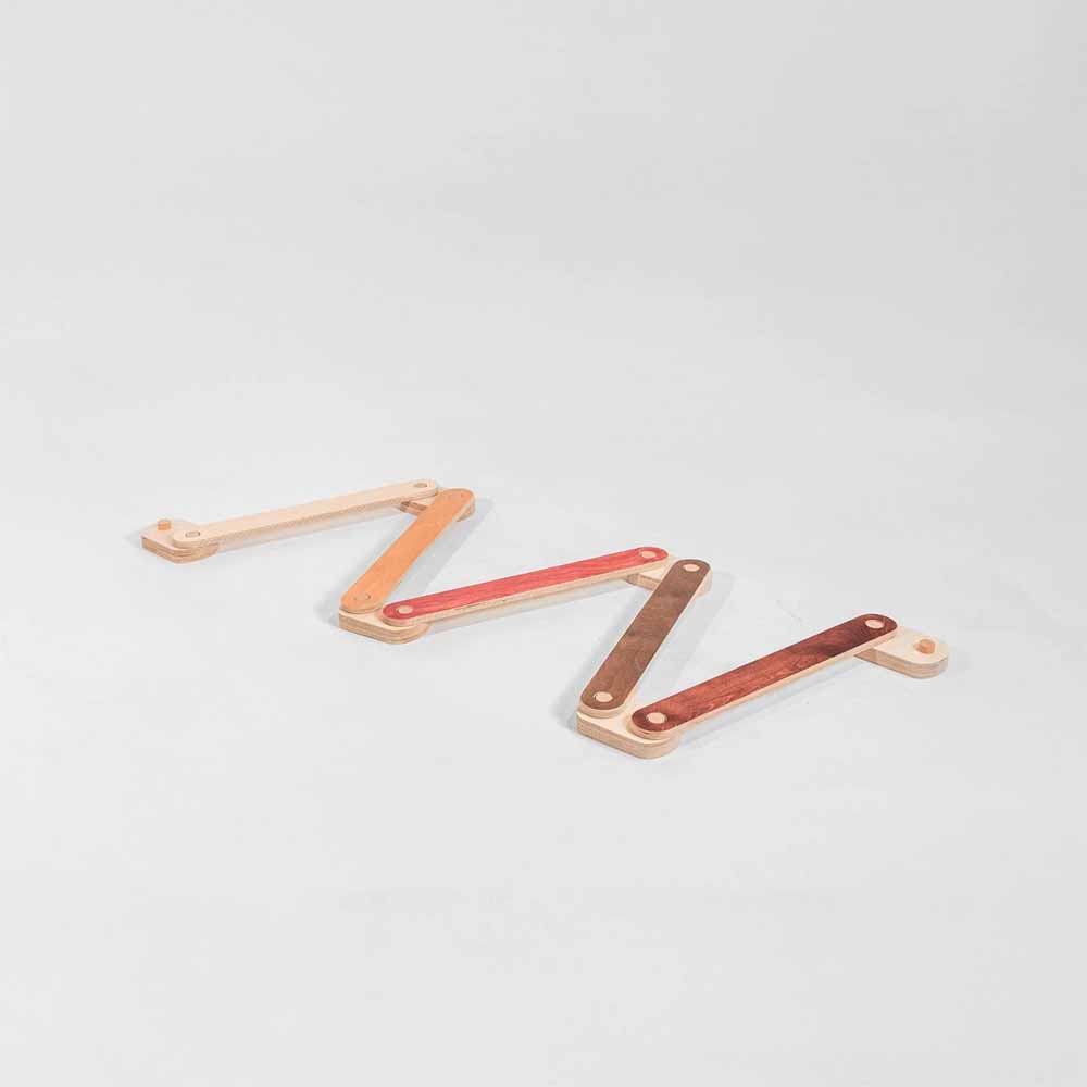 Wooden multi colored natural balance beam on a light gray background