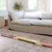 Colorful wooden balance beam on a carpeted floor with a beige sofa in the background.