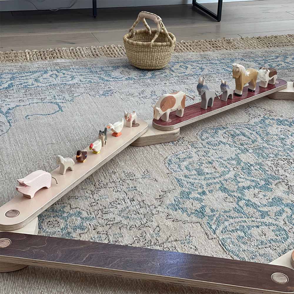 Wooden balance beam set with animals on a patterned rug