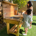 Children playing with a wooden outdoor play kitchen set in a garden.