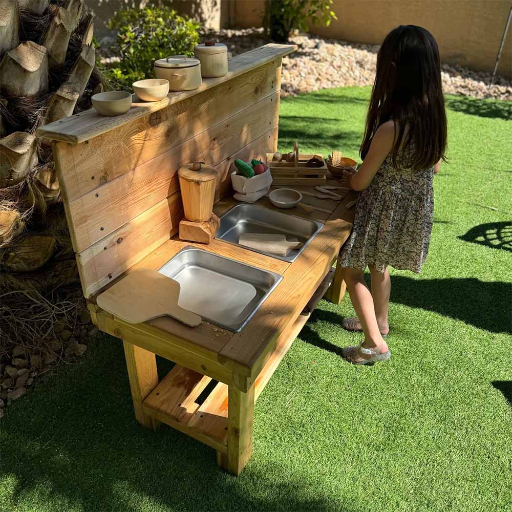 Child playing with a wooden outdoor play kitchen set on grass