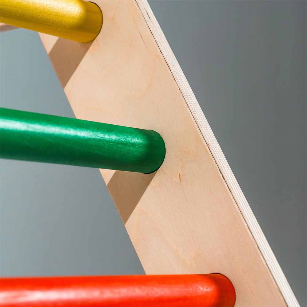 Close-up of a wooden structure with colorful wooden bars on a gray background