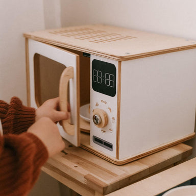 Wooden toy microwave with digital display and control knob on a wooden surface.