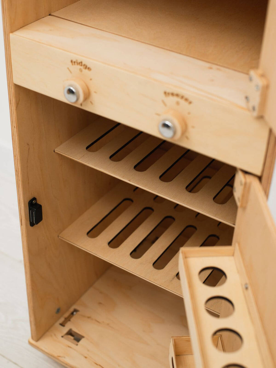 Wooden toy refrigerator with shelves and a door on a white background
