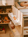 Wooden toy refrigerator with open drawers containing food items