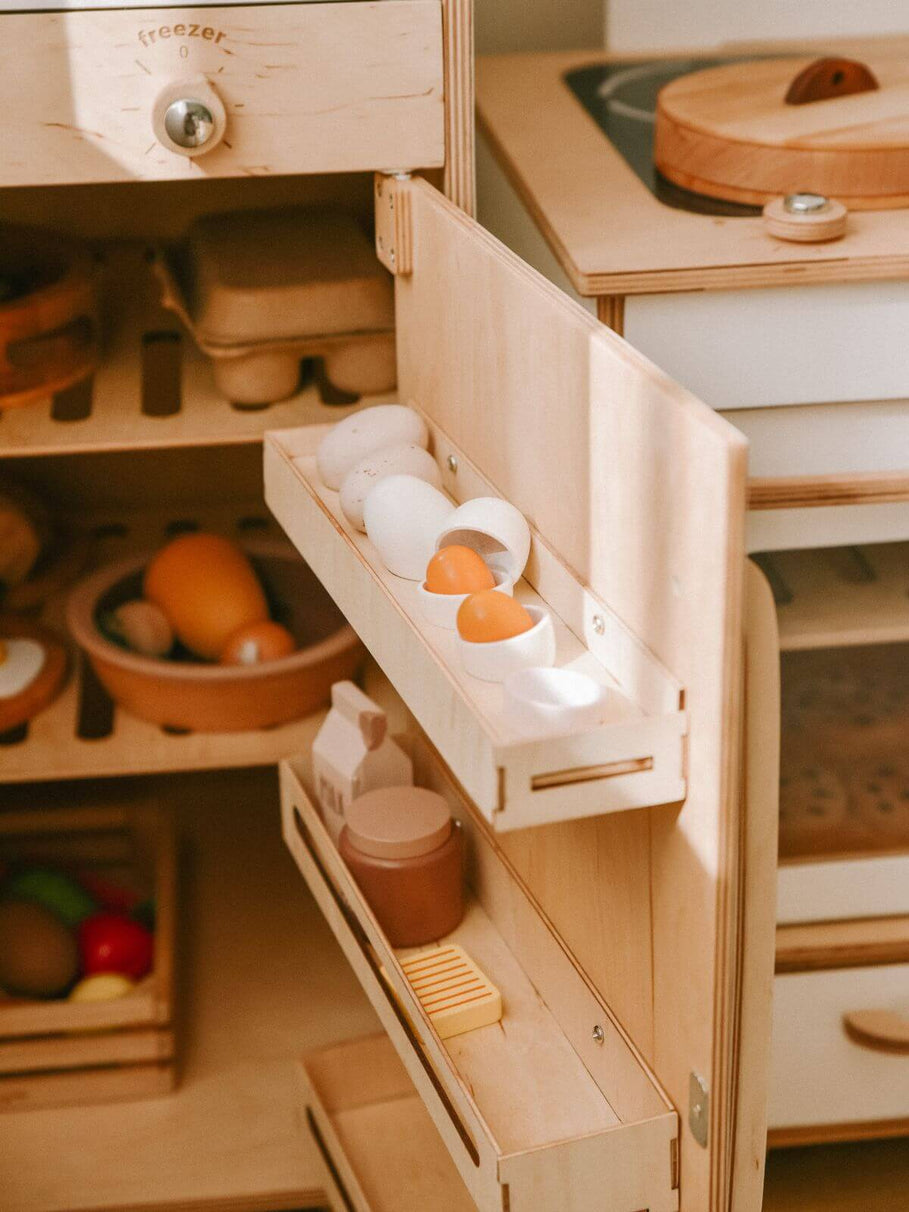 Wooden toy refrigerator with open drawers containing food items