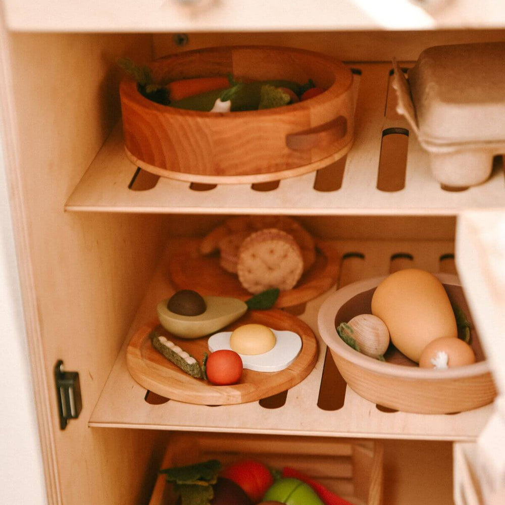 Wooden toy kitchen set with shelves containing various food items.