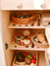 Wooden toy refrigerator with shelves containing toy food items.