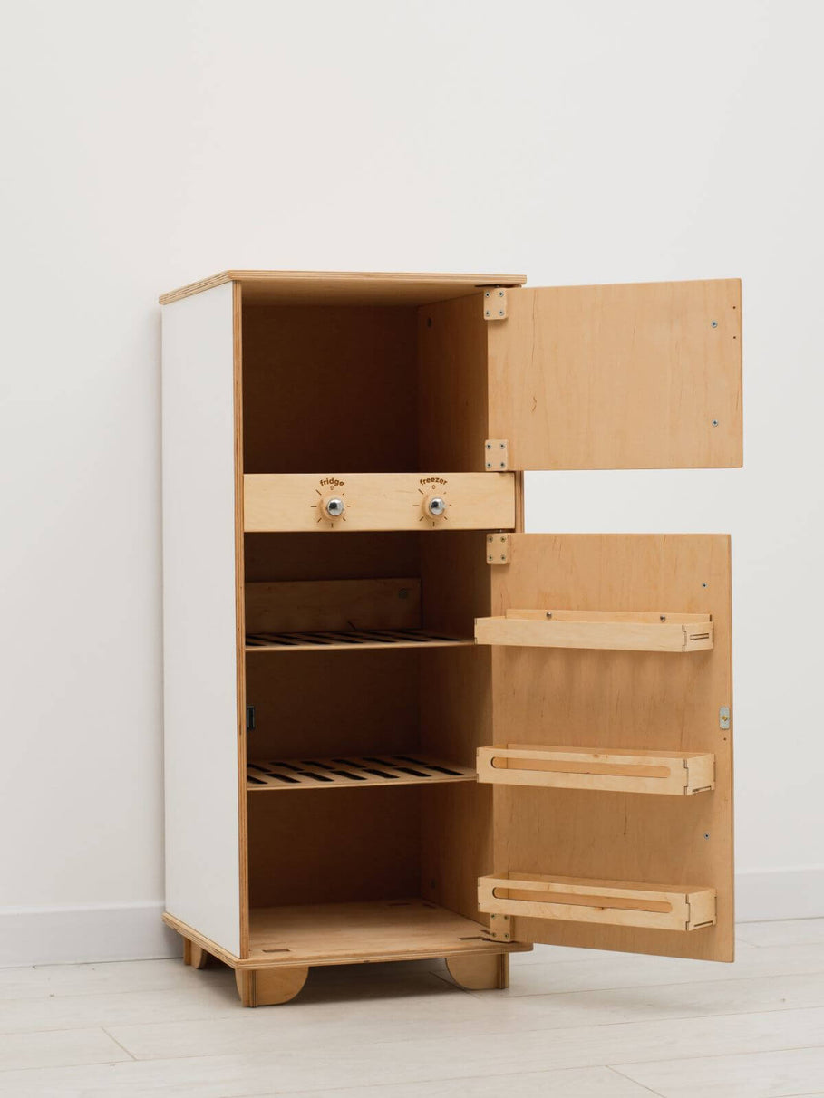Wooden play refrigerator with open doors on a white floor and wall