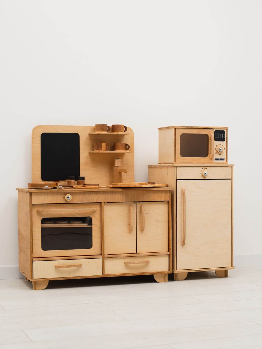 Wooden toy kitchen set with oven, microwave, and refrigerator on a white background