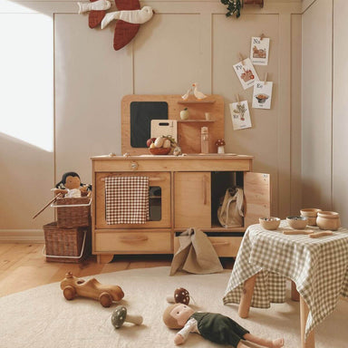 Wooden play kitchen set in a child's room with toys and decorations.