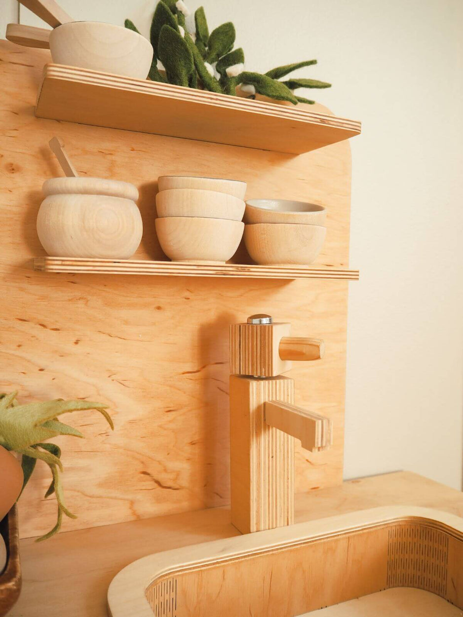 Wooden shelves with bowls and a faucet on a play kitchen