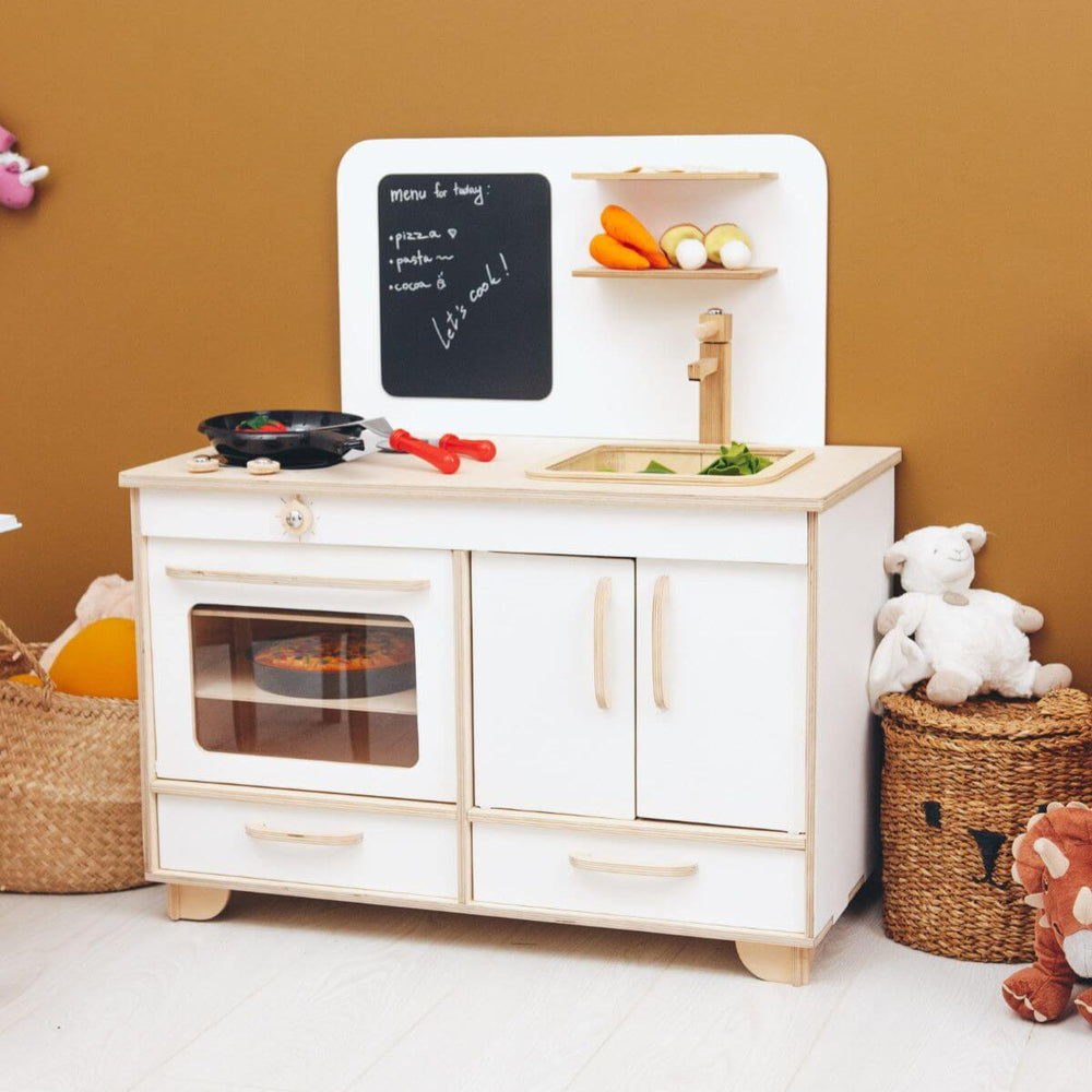 Children's play kitchen set with oven, sink, and shelves against a brown wall.
