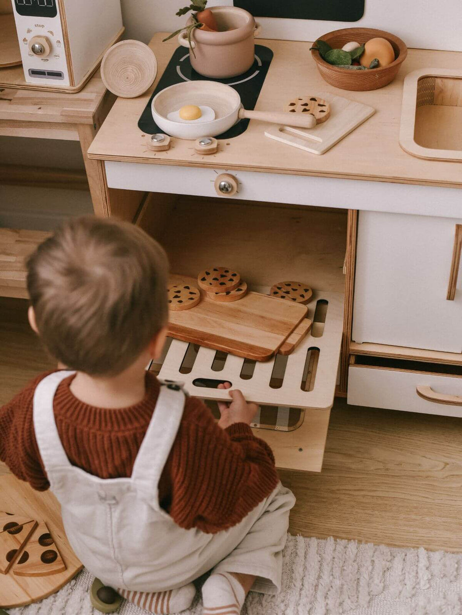 Child playing with a wooden play kitchen set