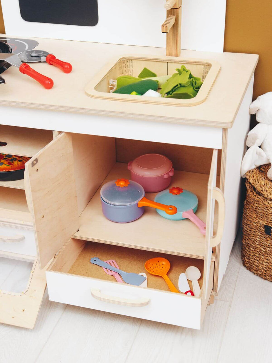 Children's play kitchen set with toy pots, pans, and utensils on a wooden shelf.