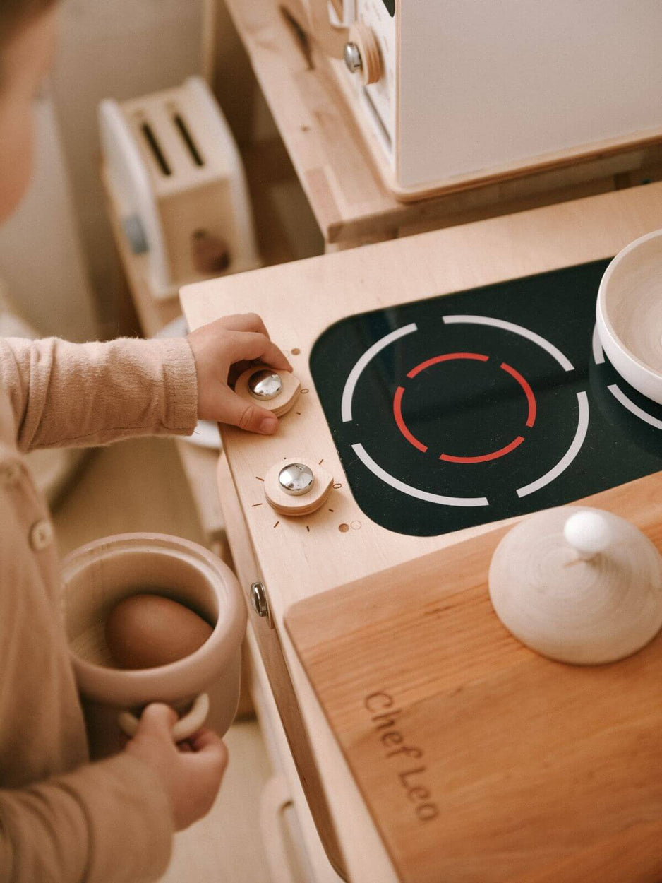 Child playing with a wooden toy kitchen set