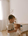 Child playing with a toy microwave in a bright room