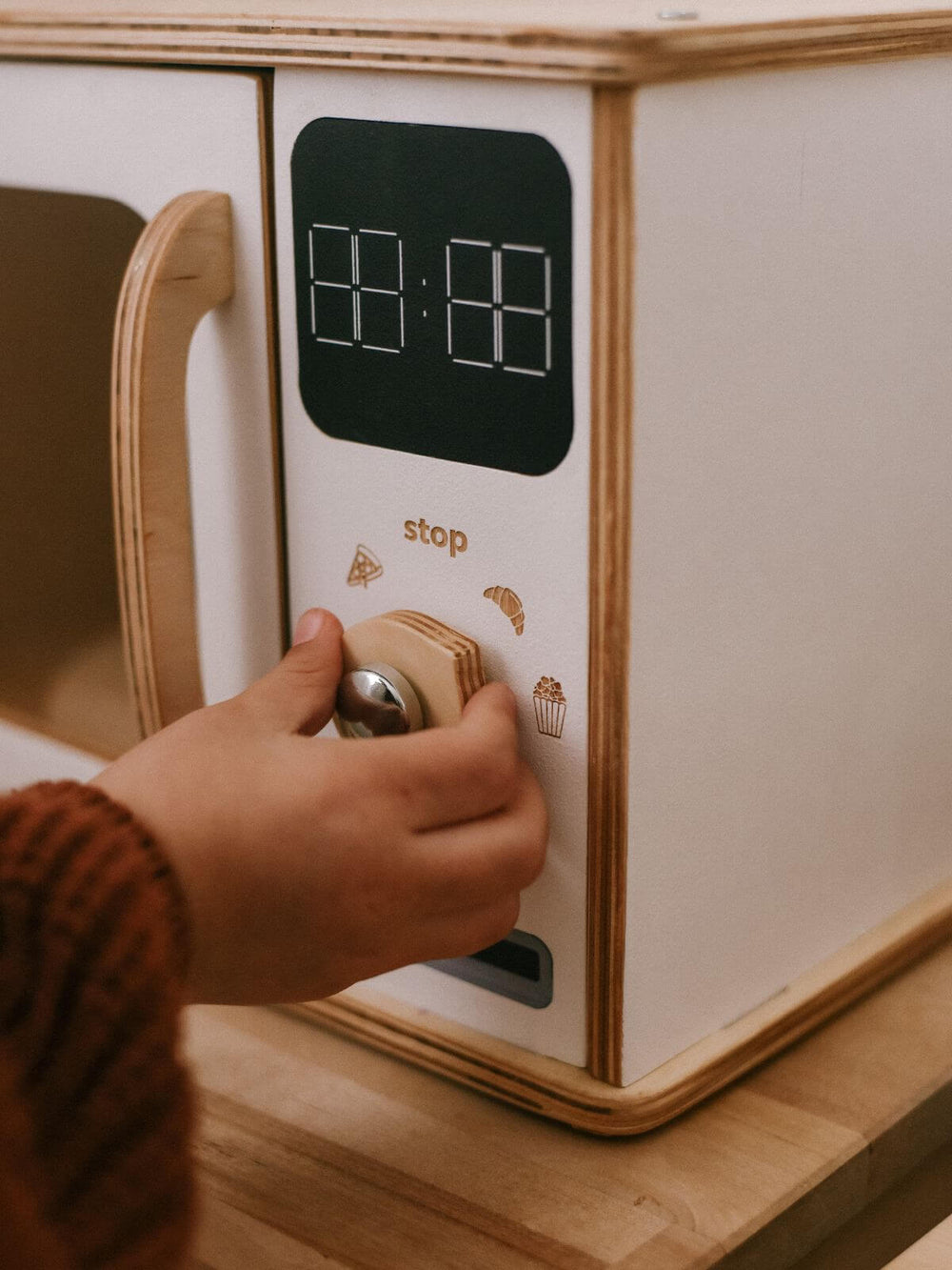 Wooden toy microwave with play timer panel and hand interacting with it