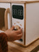 Wooden toy microwave with play timer panel and hand interacting with it
