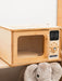 Wooden toy microwave with digital display and control panel, featuring a plush elephant toy below.