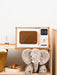 White wooden play microwave on a play shelf with a stuffed elephant below
