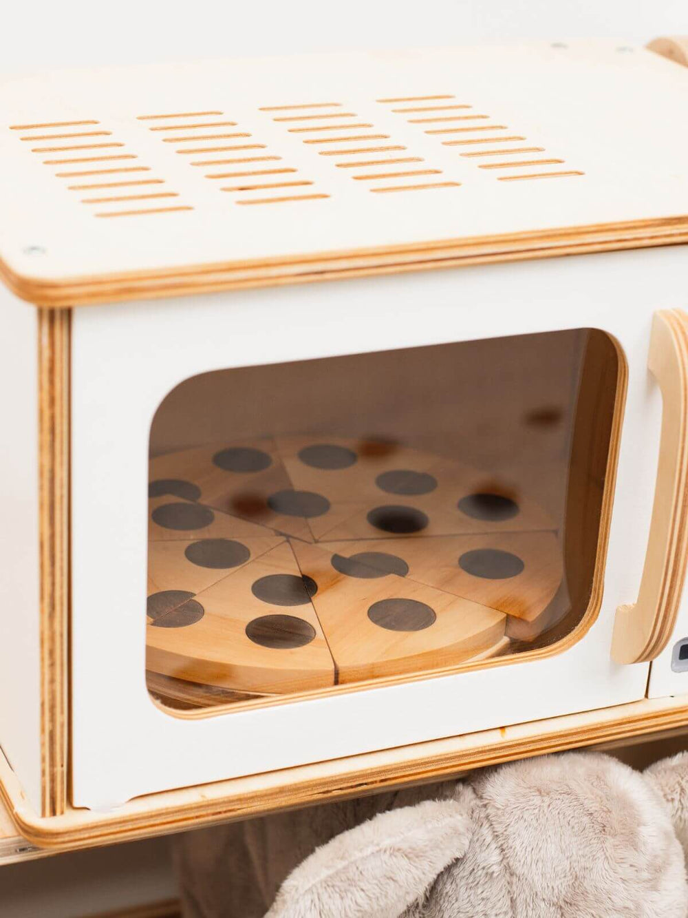 Wooden toy pizza cooking in a white wooden toy microwave