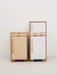 Two wooden play refrigerators, one light wood and one white, on a white floor with a white wall background.