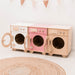 Wooden toy washing machine with round doors on a light background
