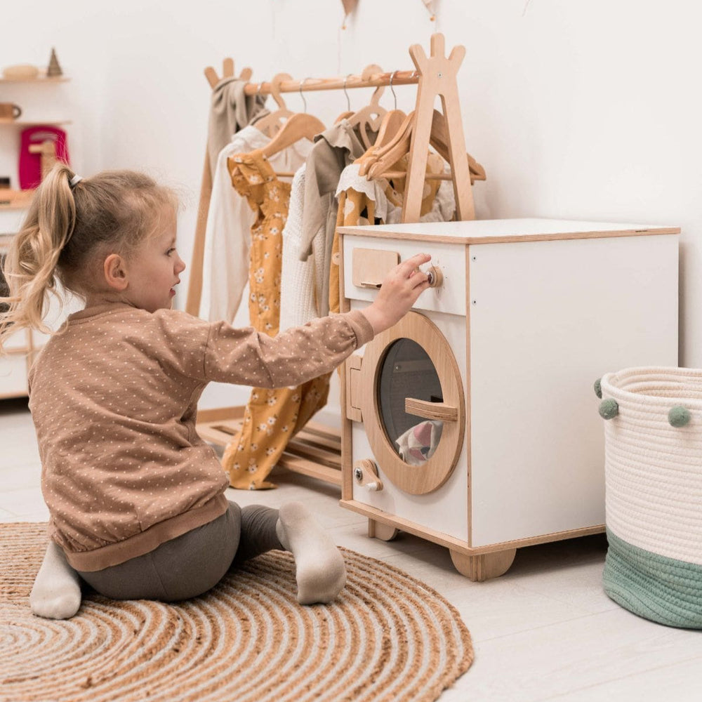 Child playing with a wooden toy laundry set in a bright room.