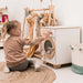 Child playing with a wooden toy laundry set in a bright room.