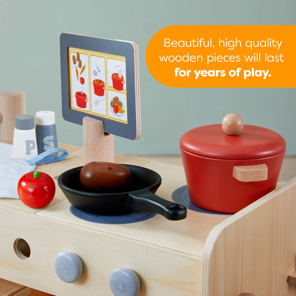 Wooden toy kitchen set with a red pot, black pan, and colorful card on a light blue background.