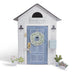 Decorative house model with a blue door, wreath, and decorative elements on a white background