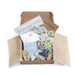 Open cardboard box with decor items including a 'Welcome Home' sign, cards, and decorative elements.