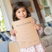 Young girl holding a 'Deed of Ownership' certificate in a living room setting.
