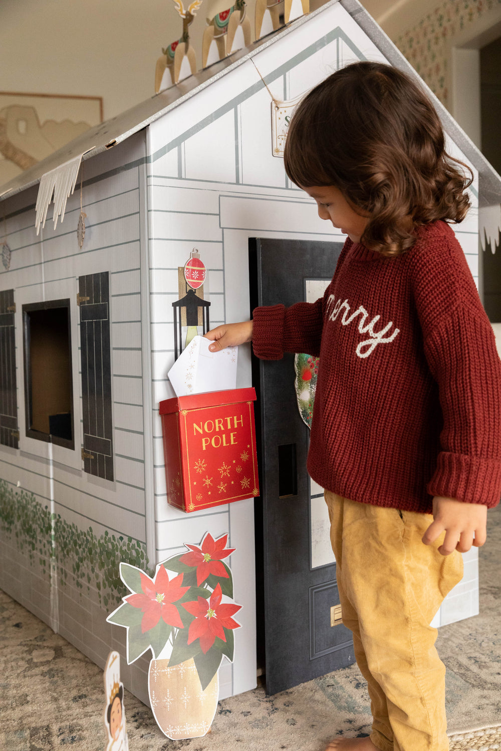Child playing with a toy house and letterbox in a cozy indoor setting