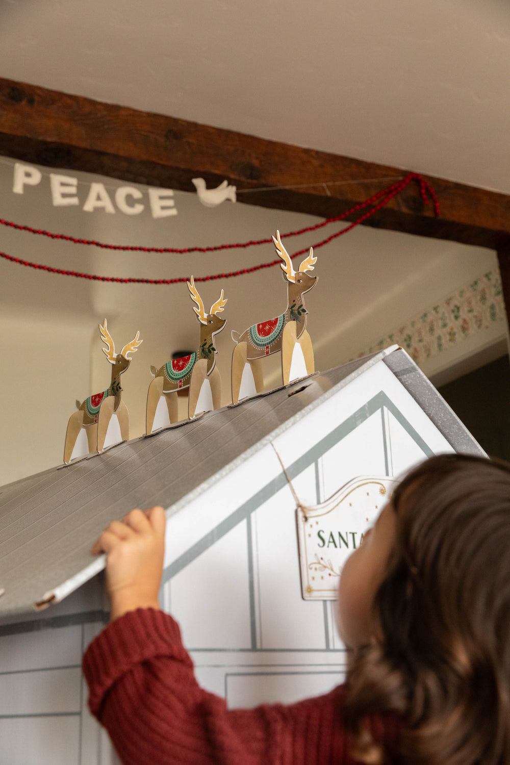 Person interacting with a Christmas-themed playhouse featuring reindeer.