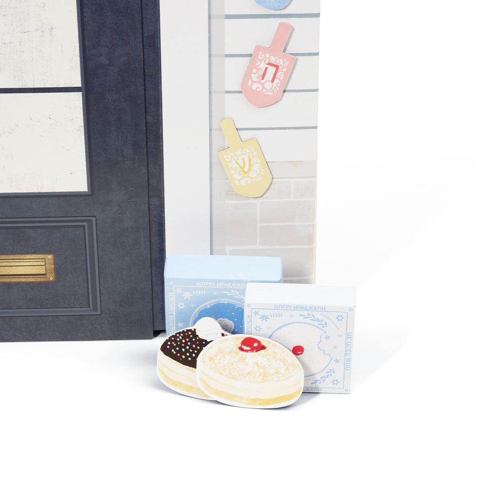 Decorative items including donuts and boxes in front of a play house on a white surface.