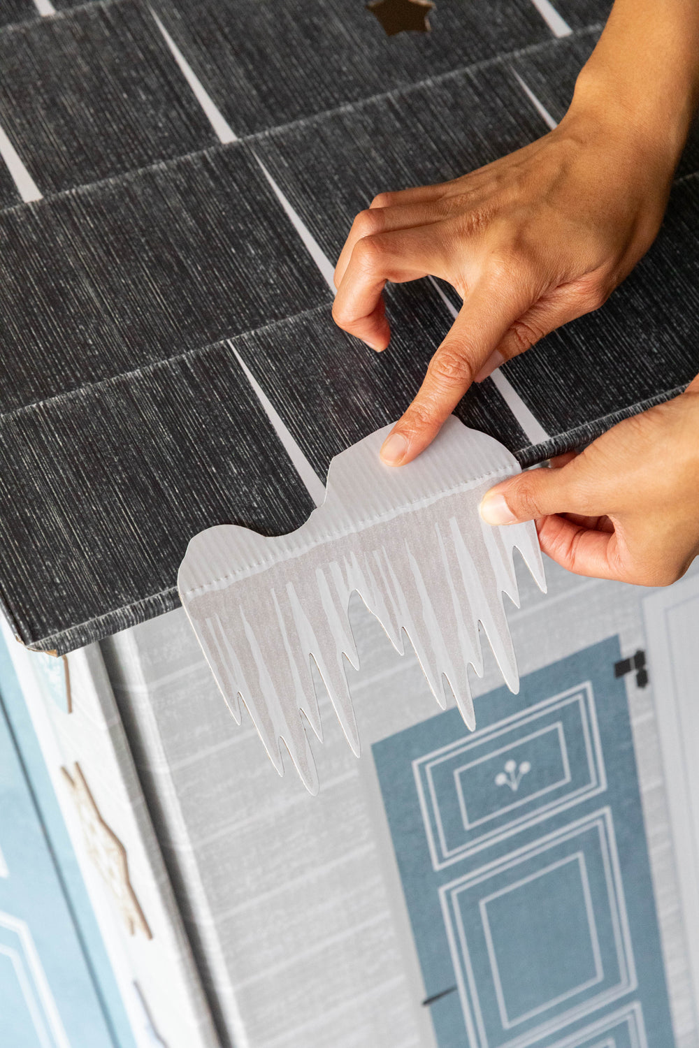 Person applying an icicle to a play house
