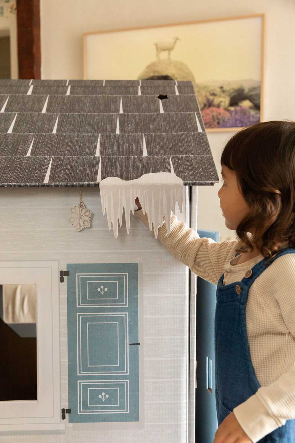Child playing with a toy house with icicles.