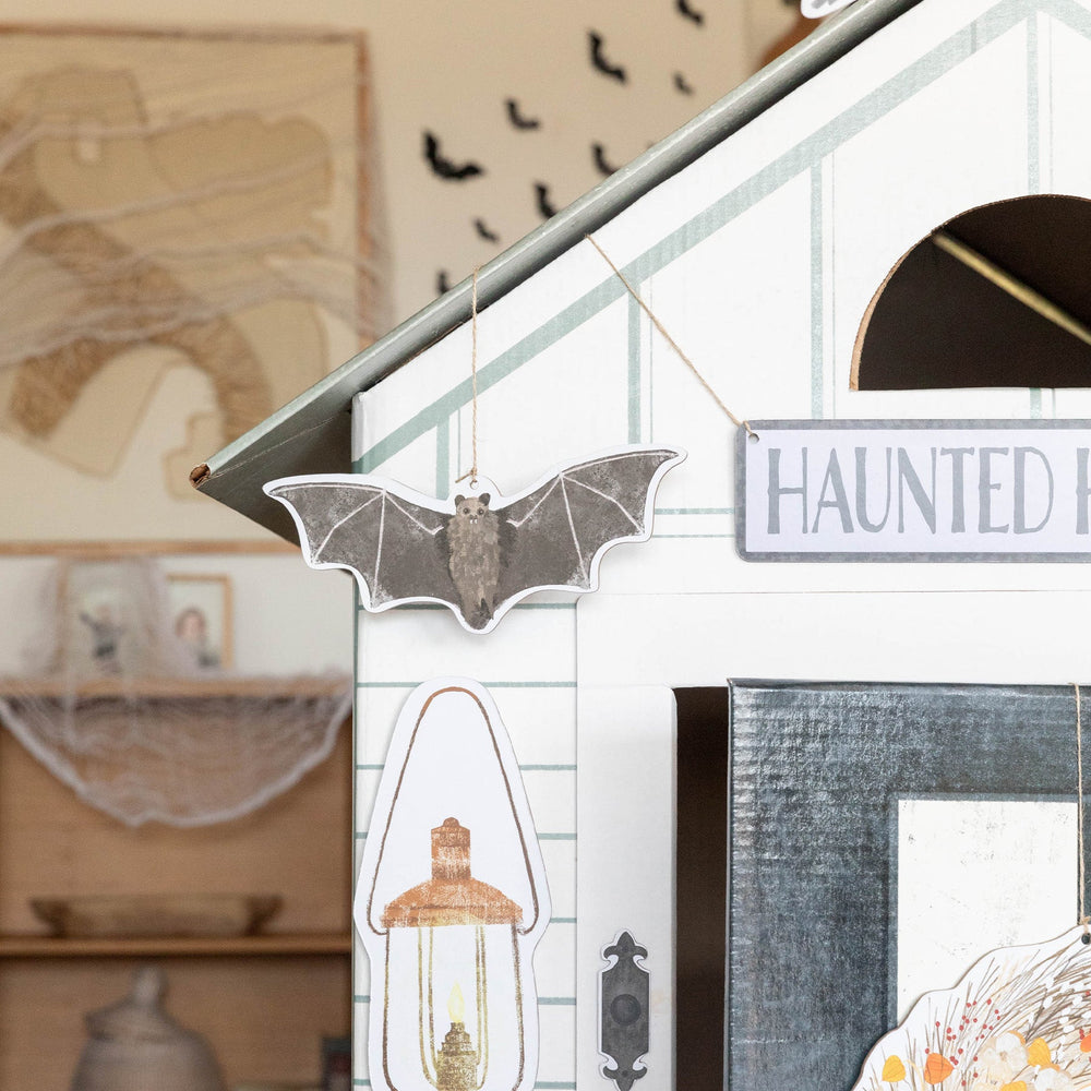 Halloween-themed decorations including a bat, lantern, and 'Haunted' sign on a white wall.