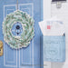 Decorative wreath on a door with a mailbox containing letters, against a blue wall.