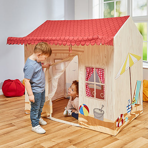 Children playing inside a play tent with a red roof on a wooden floor.