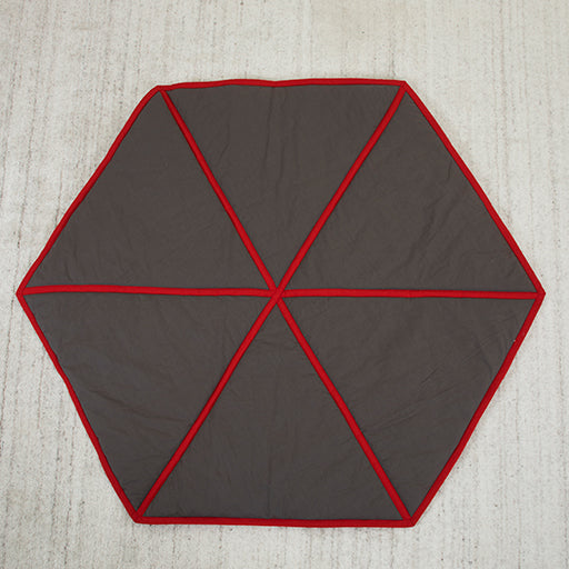Hexagonal mat with red border on a textured surface