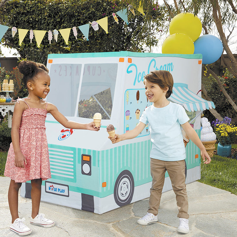 Two children holding ice cream cones in front of an ice cream truck play tent