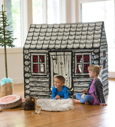 Children playing inside a log cabin play house with black and white design.