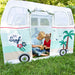 Children playing inside a vintage van-shaped play tent with palm trees and 'Surf Club' design on a grassy background.