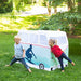 Two children playing with a vintage-style camper van play tent outdoors.