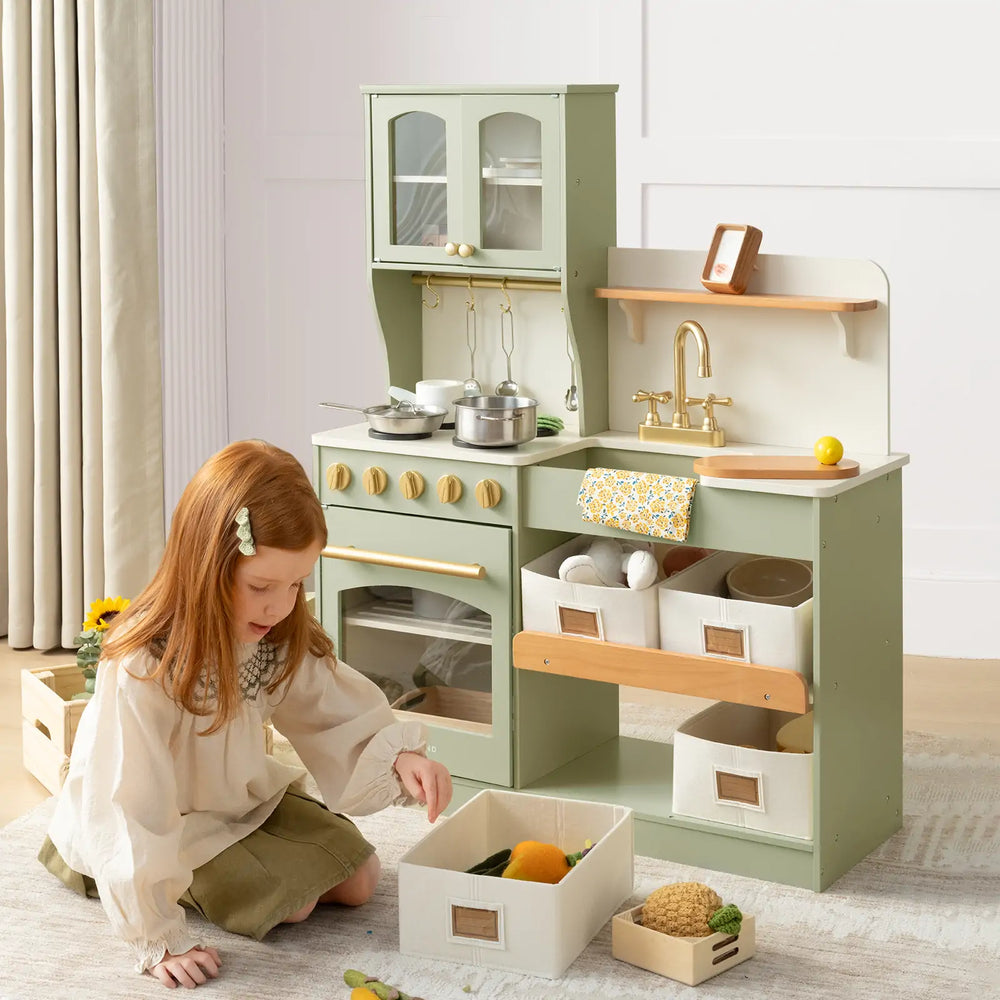Child playing with a green toy kitchen set in a room.